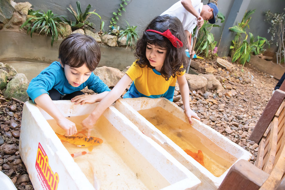 Two preschool students play with fish.